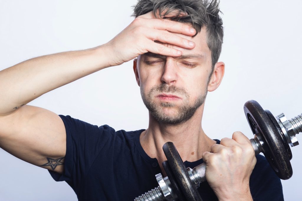 man in black shirt holding a dumbbell and looking tired